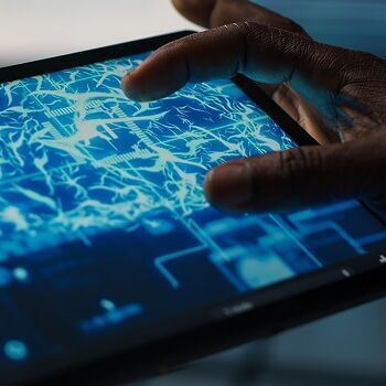 tablet_KI Eine Person bedient ein Tablet, auf dessen Bildschirm ein digitales Gehirn mit leuchtenden neuronalen Verbindungen dargestellt ist. Das Motiv symbolisiert Künstliche Intelligenz, maschinelles Lernen und die Verarbeitung komplexer Daten in einer vernetzten, digitalen Umgebung.